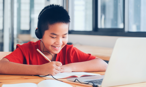 Little boy sitting in front of laptop working on homework
