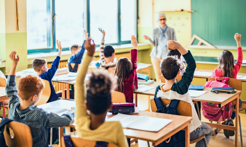 Kids raising hands to answer a question in the classroom