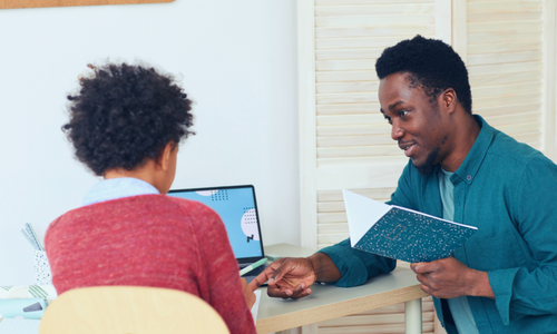 Man and child sitting at desk and working on laptop