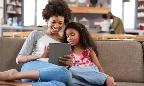 Woman and little girl looking at tablet and smiling