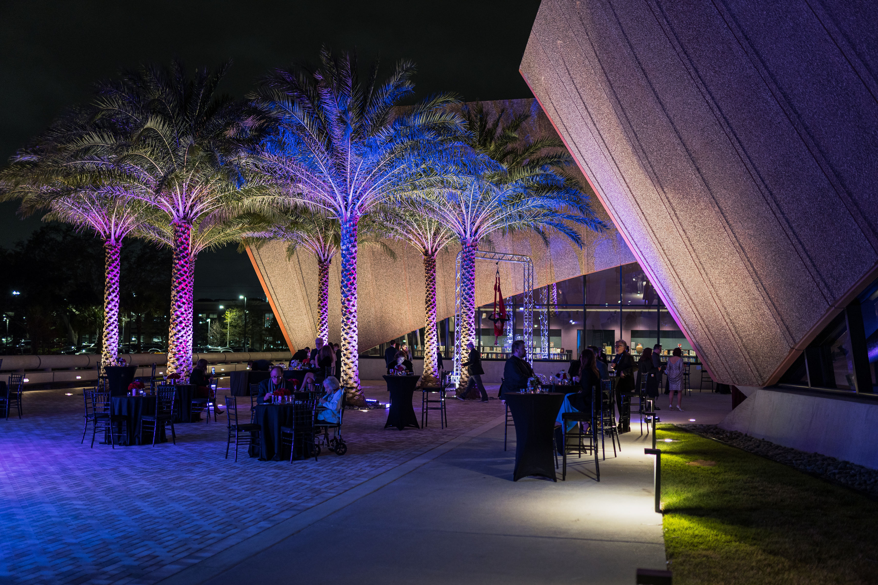 Gala image showing guests seated outside with lit palm trees