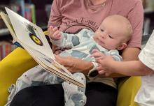 Baby on someone's lap with open book